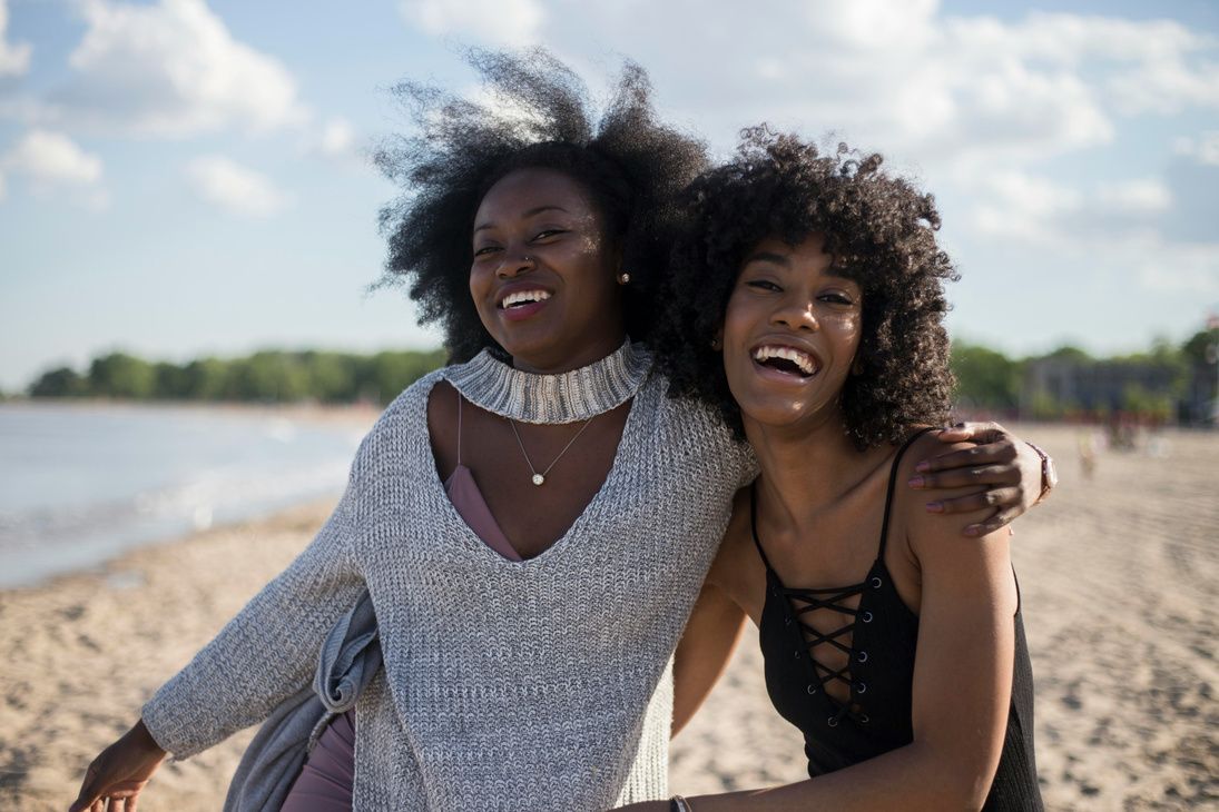 Two friends laughing together on the beach