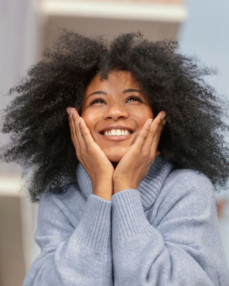 Woman smiling joyfully, hands resting on her face