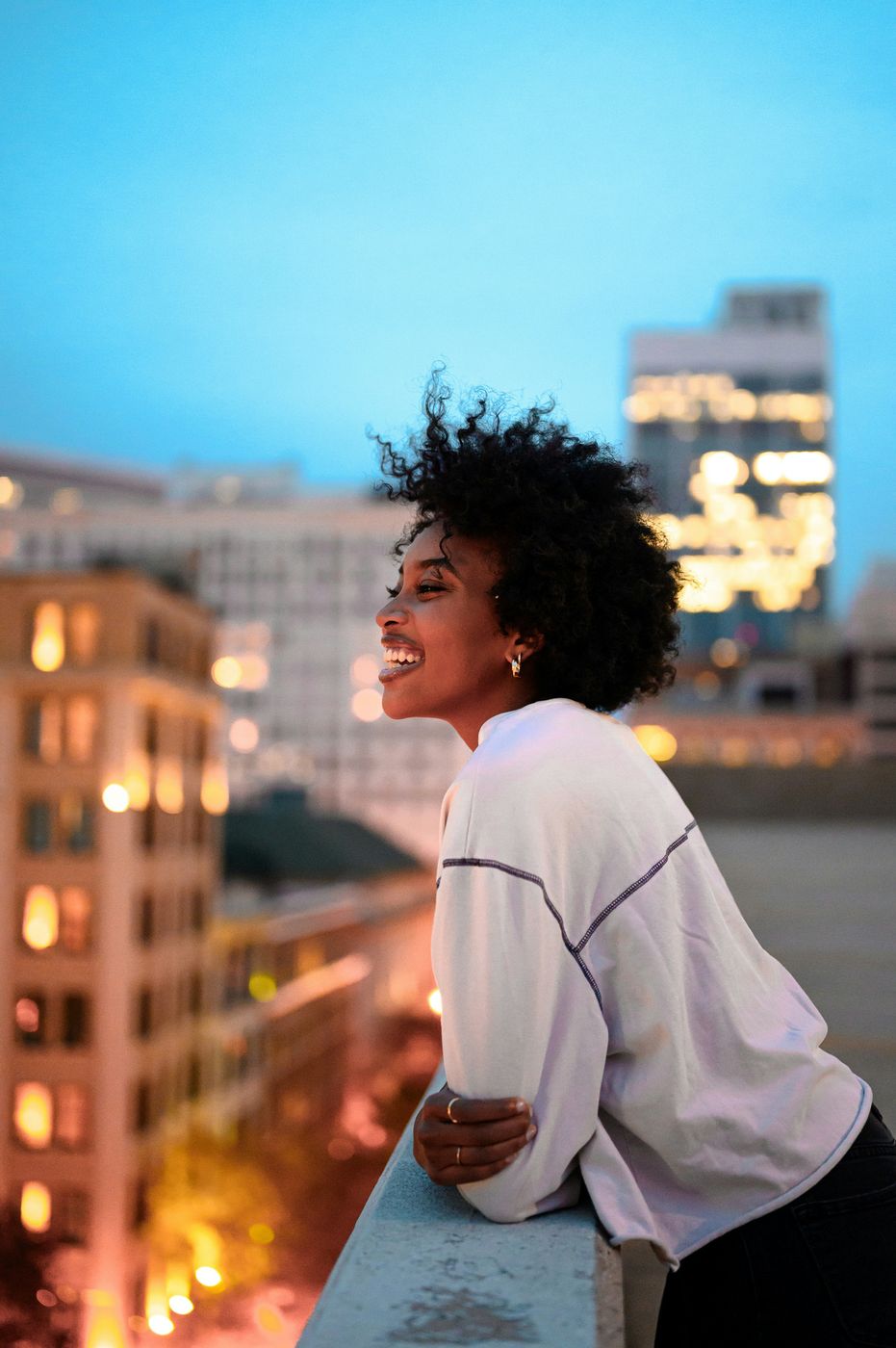 Woman smiling joyfully on a rooftop at dusk